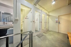 A hotel corridor with doors leading to rooms, a staircase, and a bench.