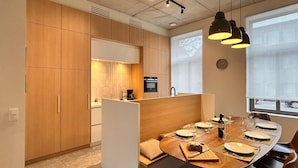 Una cucina moderna con mobili in legno, forno a incasso e zona pranzo con tavolo rotondo per quattro persone.
