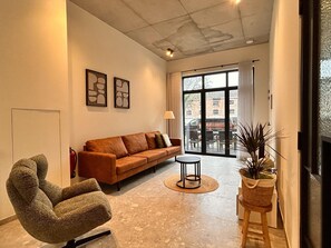 Uma sala de estar moderna com sofá, poltrona e uma pequena mesa redonda.