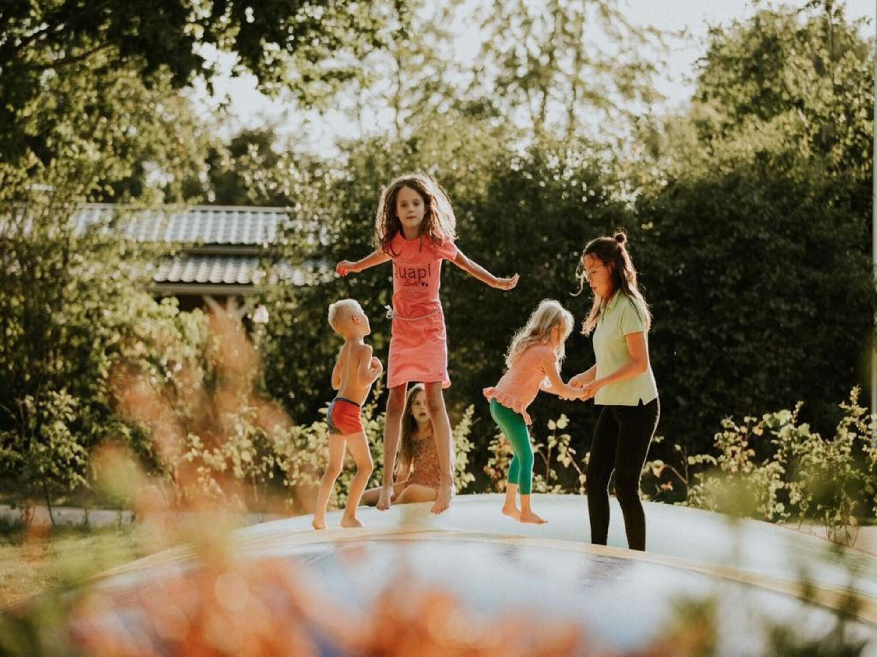 A trampoline in an outdoor setting with trees and a building in the background.