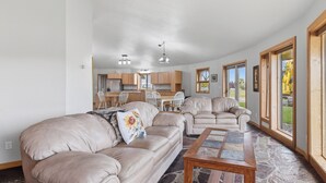Un salón espacioso con un sofá color beige, una mesa de centro y vistas a la cocina al fondo.