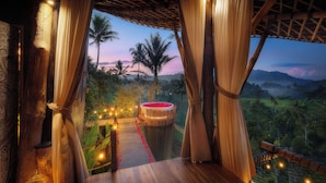 A wooden deck with a view of a lush landscape, including palm trees and distant mountains. - Camaya Bali (Selat)