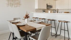 Una cocina moderna con armarios blancos, encimera de madera y una isla central.