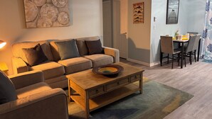 A living room with a sofa, coffee table, and a dining area with chairs and a table.