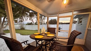 A covered patio with a round table set for four, surrounded by wicker chairs.