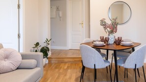 Un comedor con una mesa redonda, sillas tapizadas en gris y un jarrón con flores.
