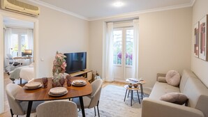 Una sala de estar moderna con comedor, televisor de pantalla plana y sofá.