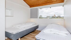 A small, single-room accommodation with two beds, a window with a view, and a wooden ceiling. - Vigso Feriecenter in Hanstholm (Hanstholm)