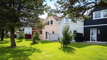 A residential area with houses, a lawn, and trees.