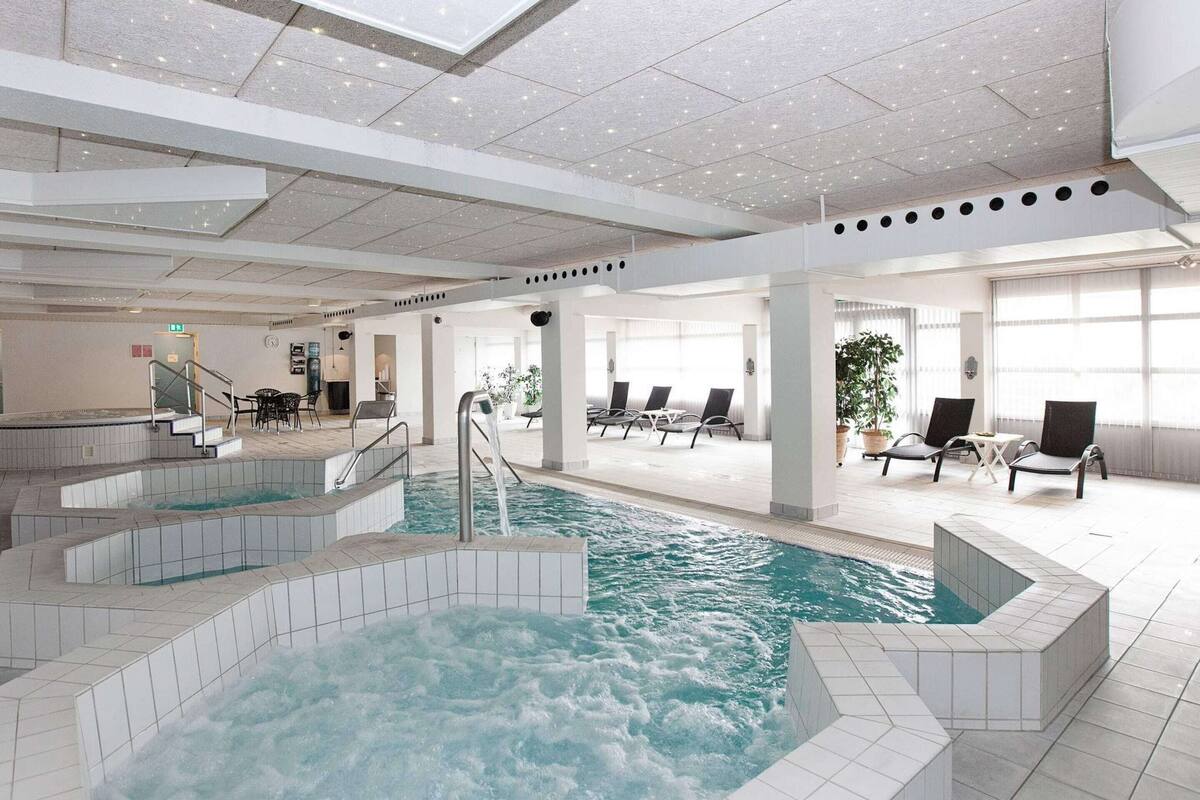 An indoor swimming pool with multiple levels and seating areas.