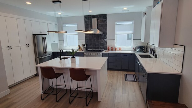 A modern kitchen with a central island, pendant lighting, and a black backsplash. - Furnished 3BR Townhome with Mountain View and Minutes from Downtown & Stadiums (Denver)