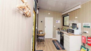 Een kleine keuken met een magnetron, spoelbak en houten aanrecht.