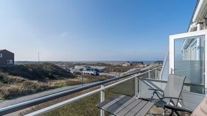 En balkon med udsigt over stranden og bygninger i det fjerne.