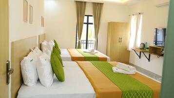 A hotel room with two beds, a wardrobe, a TV, and a window with curtains.