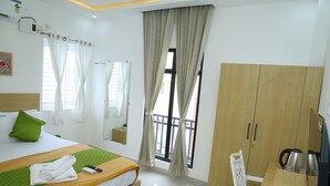 A hotel room with a bed, a desk, a chair, a wardrobe, and a balcony. - Aeroview Homestay Chennai Airport (Chennai)