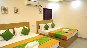 Habitación de hotel con dos camas, cada una con ropa de cama y almohadas verdes, un cabecero de madera y una colcha verde acolchada.