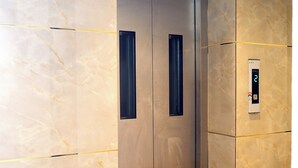 An elevator with a marble wall and a wooden floor. - Aeroview Homestay Chennai Airport (Chennai)