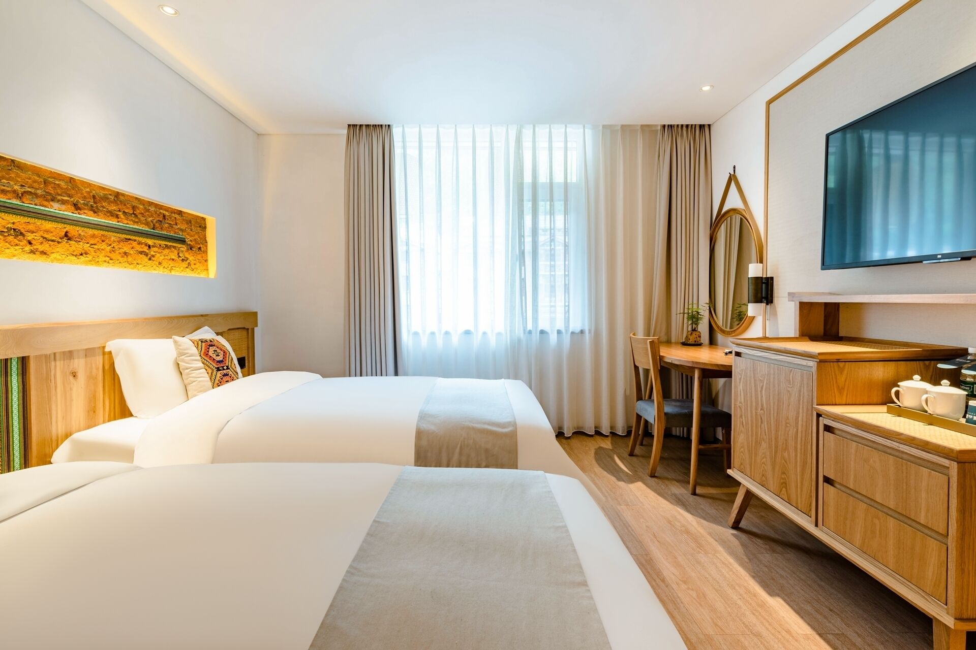 A hotel room with two beds, a desk, a TV, and a cabinet.