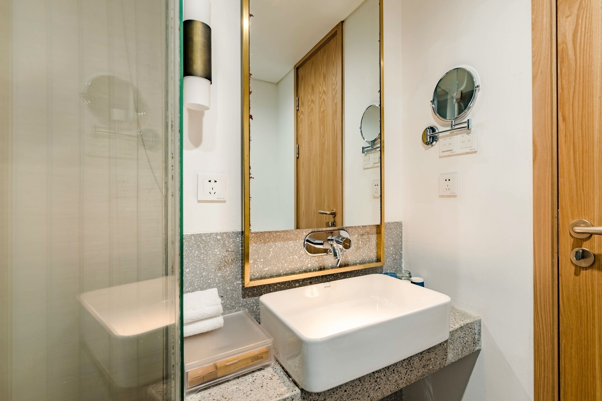 A bathroom with a white sink, a mirror, and a wooden door.