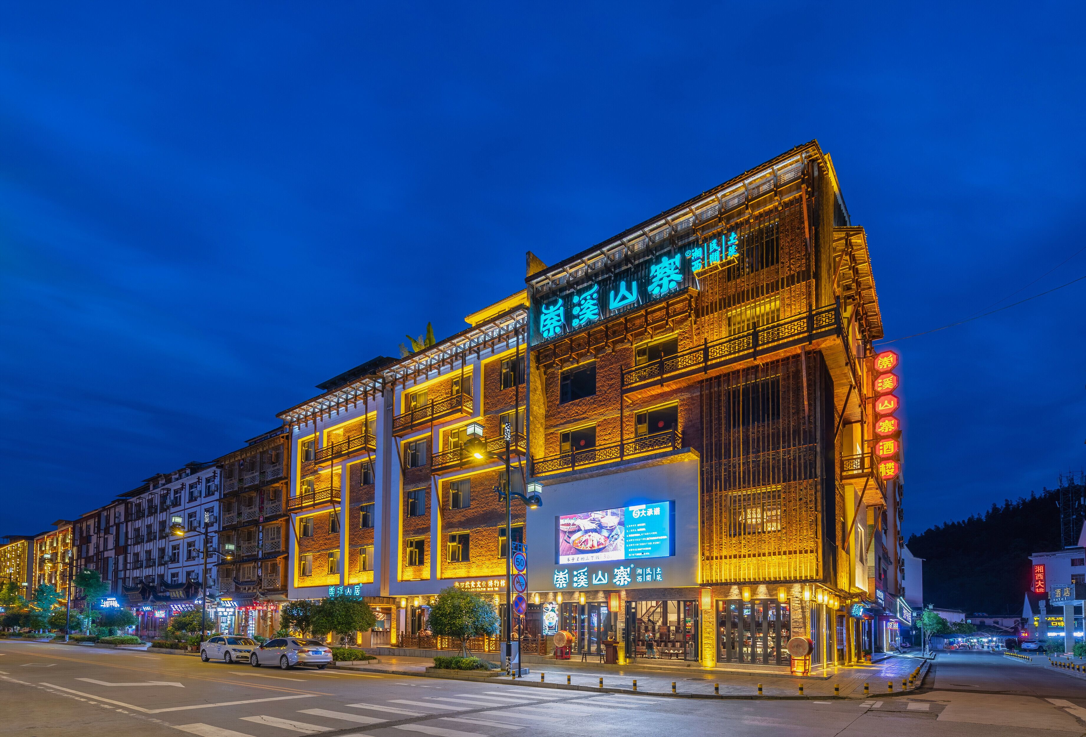 A multi-story building with illuminated signage and a large digital menu display at the ground level.