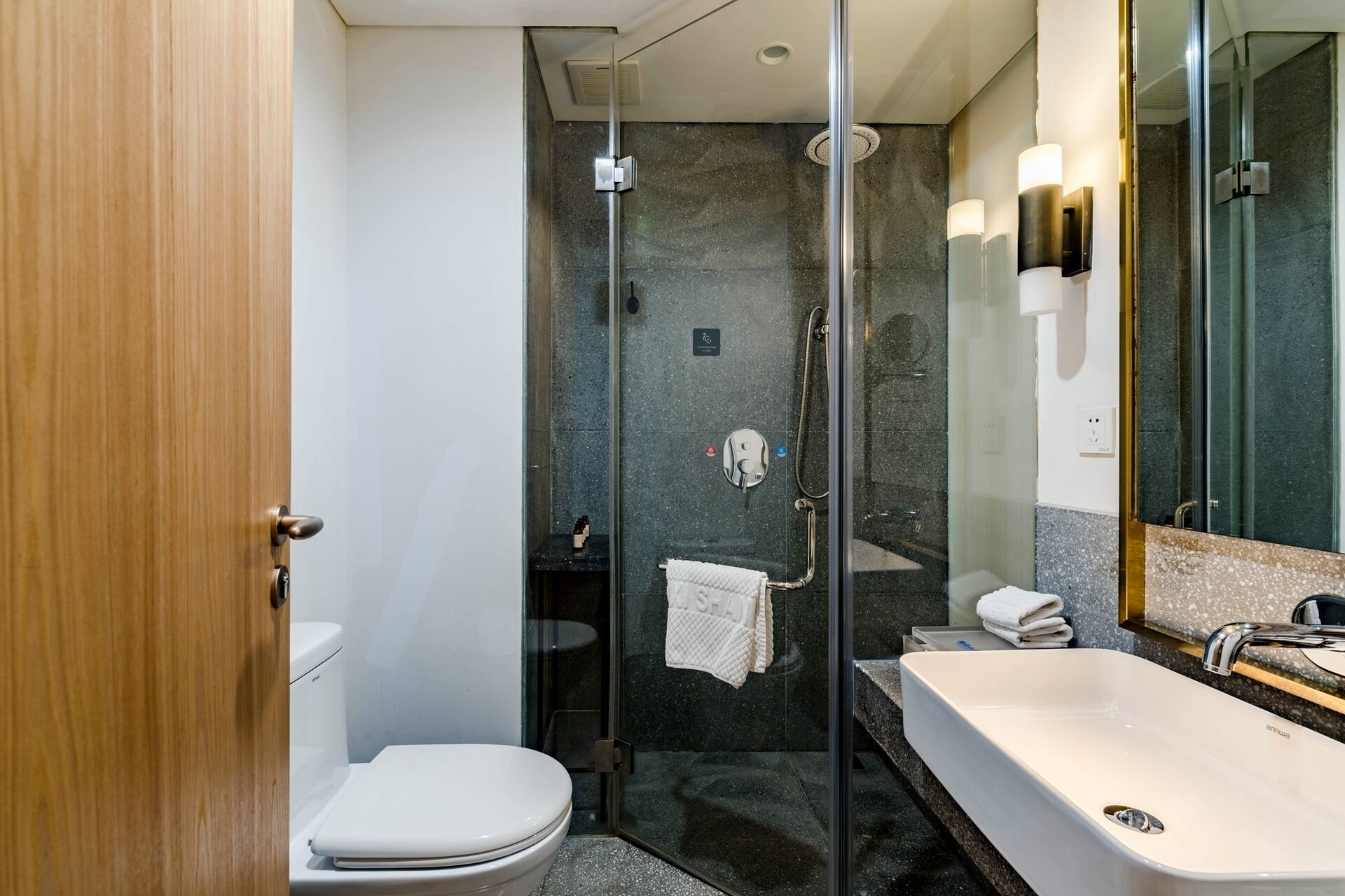A modern bathroom with a glass-enclosed shower, a white toilet, and a large white bathtub.
