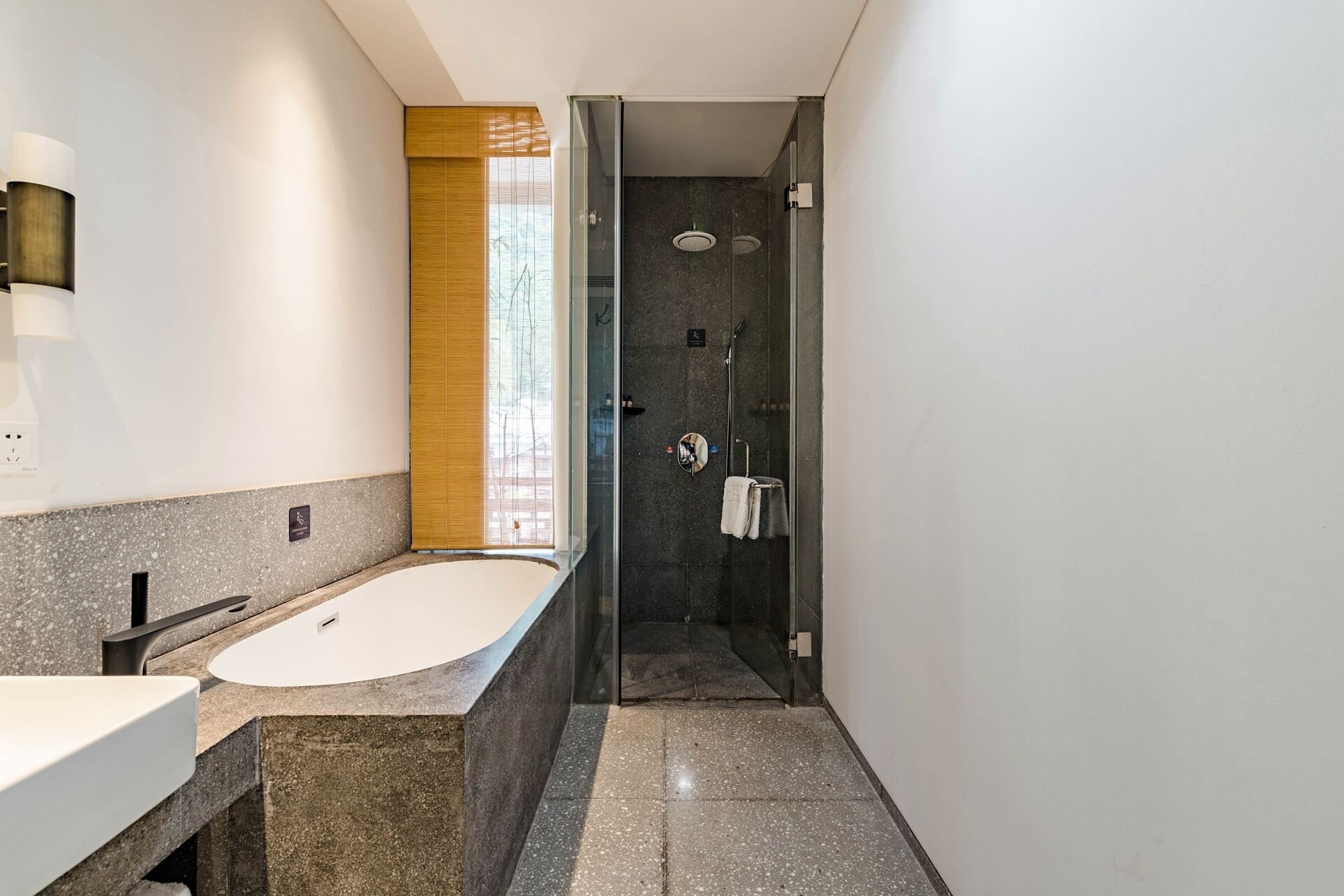 Een moderne badkamer met een vrijstaand bad, een douche met glazen wanden en een wastafelmeubel met spiegel.