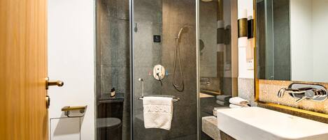 Een moderne badkamer met een douchecabine van glas, een wit toilet en een wastafel met een grote spiegel.