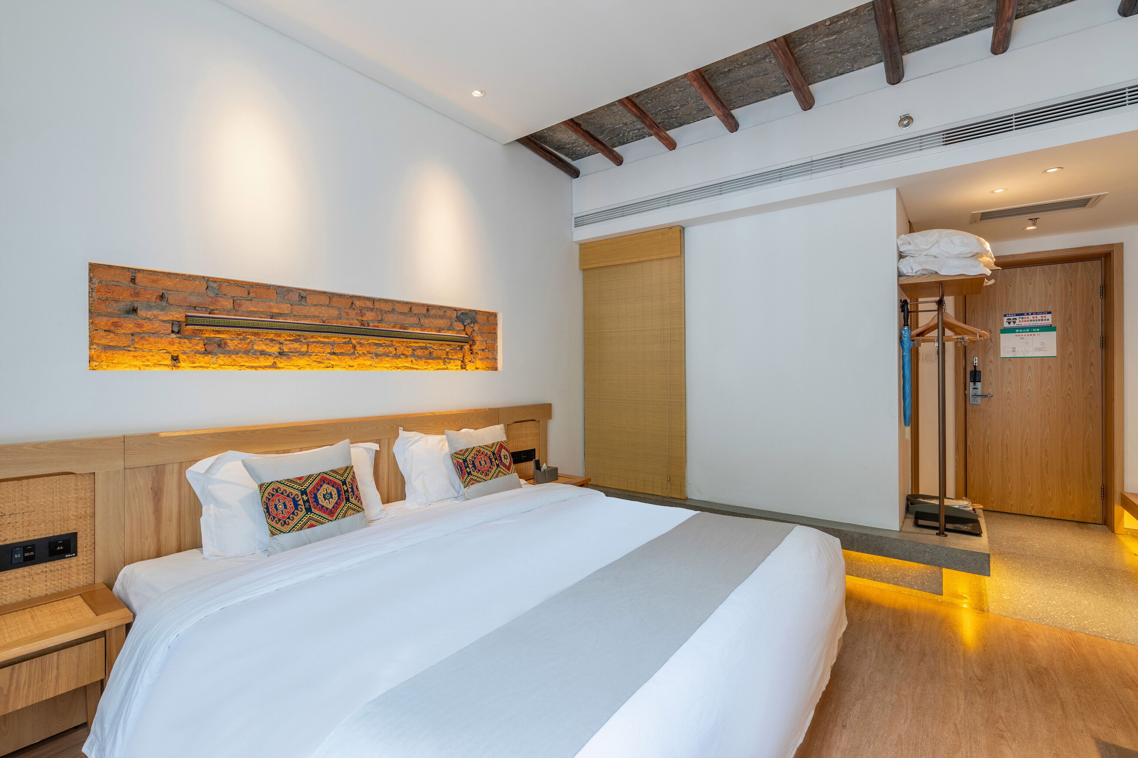 A hotel room with a large bed, wooden headboard, and a wall-mounted artwork.