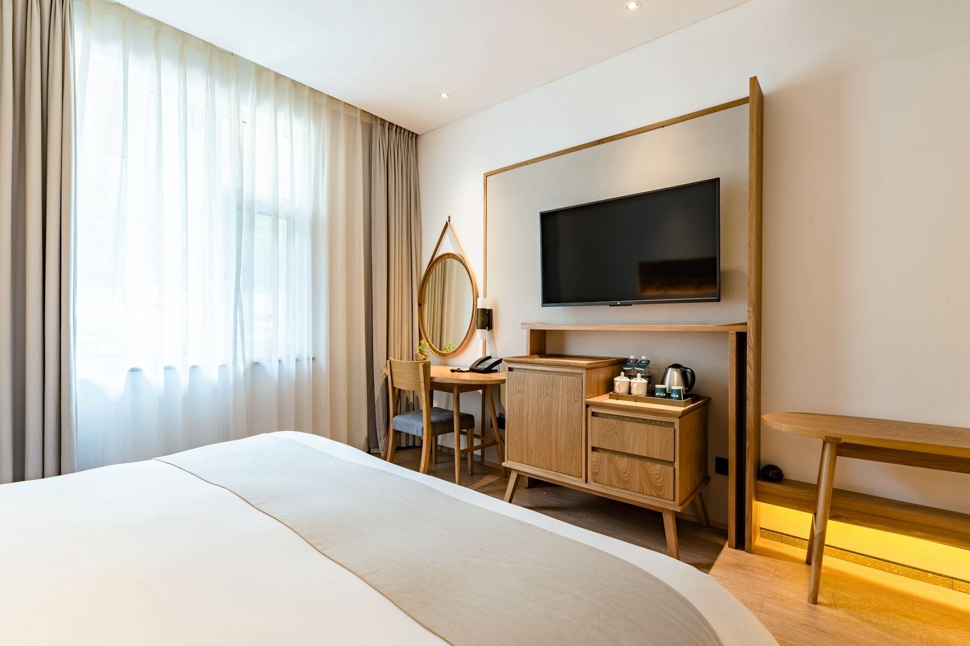 A hotel room with a large bed, a desk with a mirror, a television, and a small table.