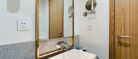 A bathroom with a white sink, a mirror, and wooden doors.