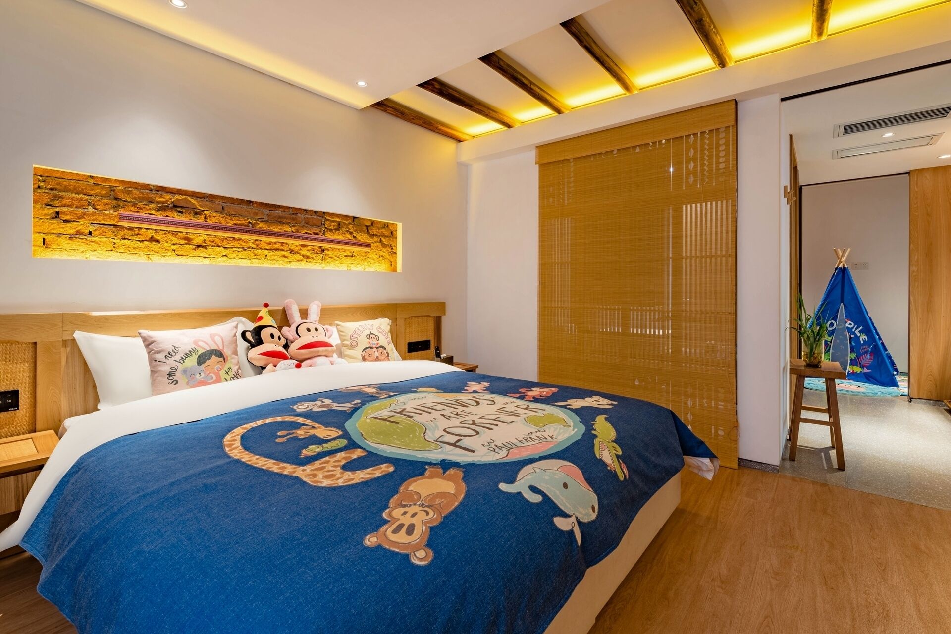 Habitación de hotel con una cama con colcha colorida, cabecero de madera y una obra de arte colgada en la pared.