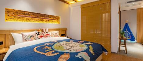 Habitación de hotel con una cama con colcha colorida, cabecero de madera y una obra de arte colgada en la pared.