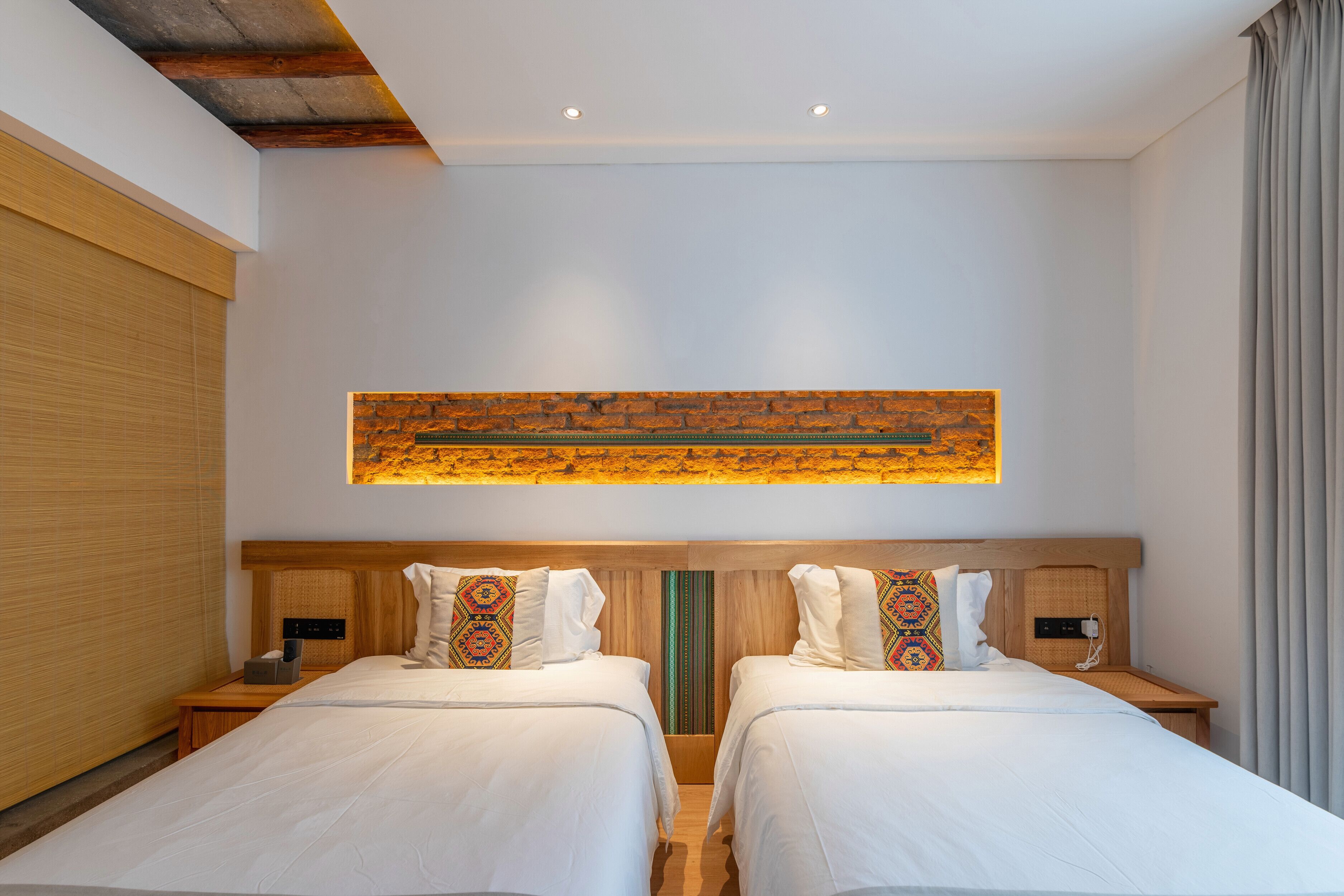 A hotel room with two beds, a wooden headboard, a wall-mounted artwork, and a bedside table with a phone.