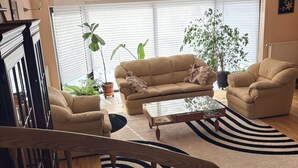 Un salon avec un canapé, un fauteuil, une table basse et des plantes en pot.