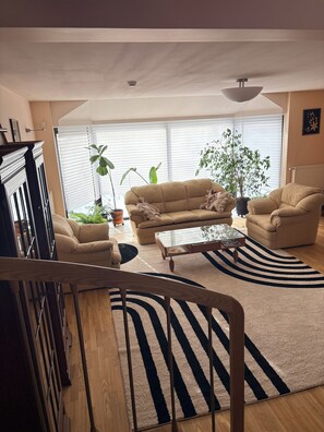 A living room with a sofa, armchair, coffee table, and potted plants.