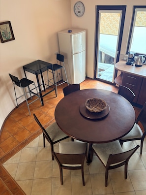 A compact kitchen with a refrigerator, a coffee maker, and a window with a view.