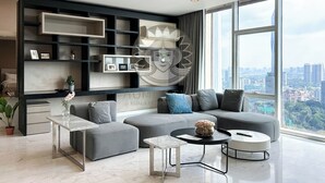 A modern living room with a grey sectional sofa, a small coffee table, and a large window offering a city view.