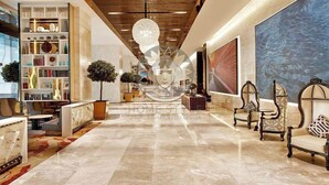 A spacious lobby with a marble floor, a large bookshelf, and a modern chandelier.