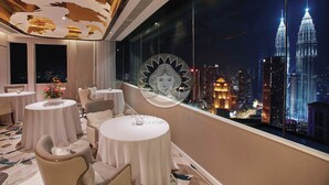 A hotel room with a view of the Petronas Towers at night.
