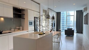 A modern kitchen with a central island, built-in appliances, and a dining area with a view of the city.
