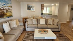 Una sala de estar con un sofá beige, una mesa de centro y un cuadro en la pared.