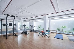 Une salle de sport spacieuse, équipée de matériel d’exercice, dotée de grandes fenêtres et offrant une vue sur l’extérieur.