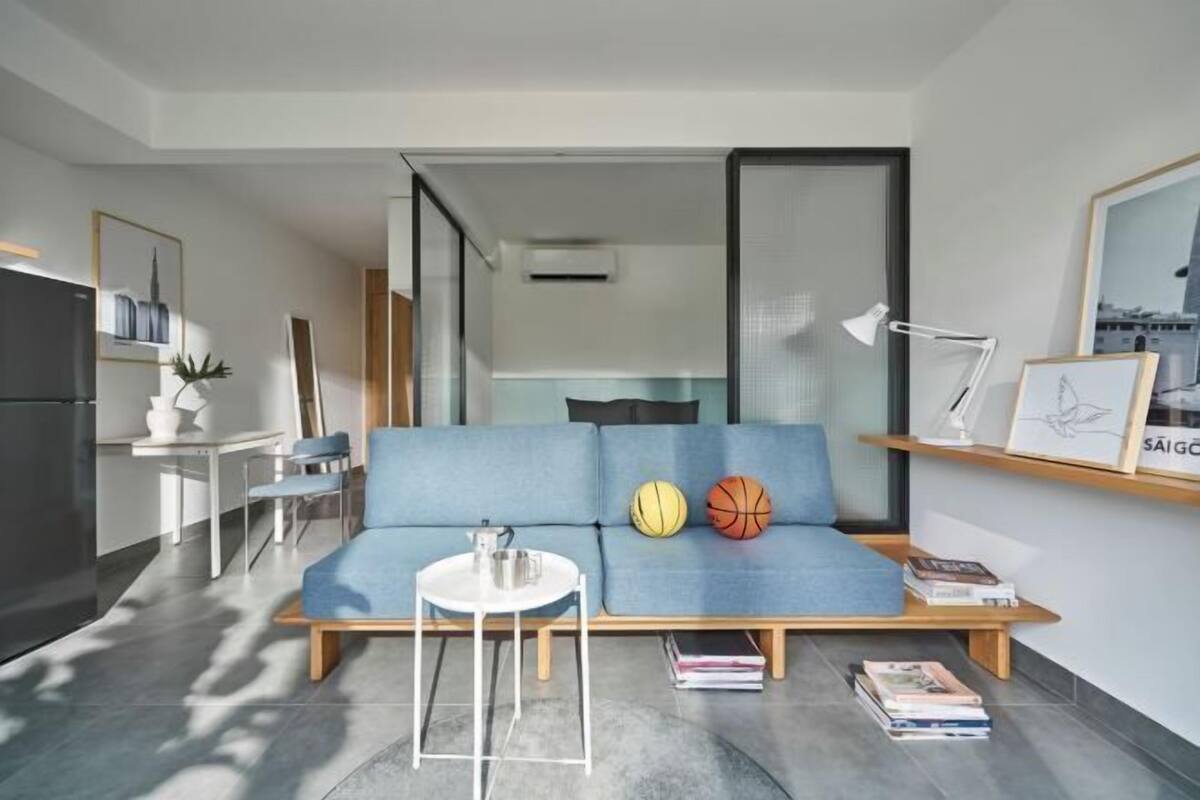 Ein modernes Wohnzimmer mit einem blauen Sofa, einem kleinen weißen Tisch und einem Bücherregal.