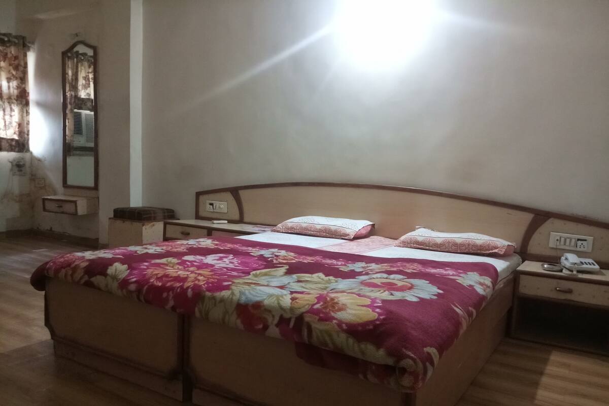 A bedroom with a bed, bedside tables, a mirror, and a wall socket.
