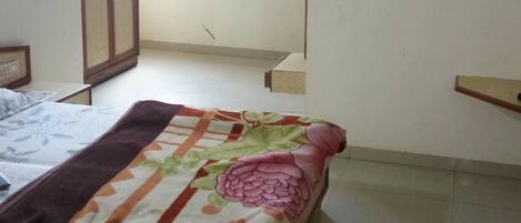 A bedroom with a bed, a wardrobe, a painting, and a small table.