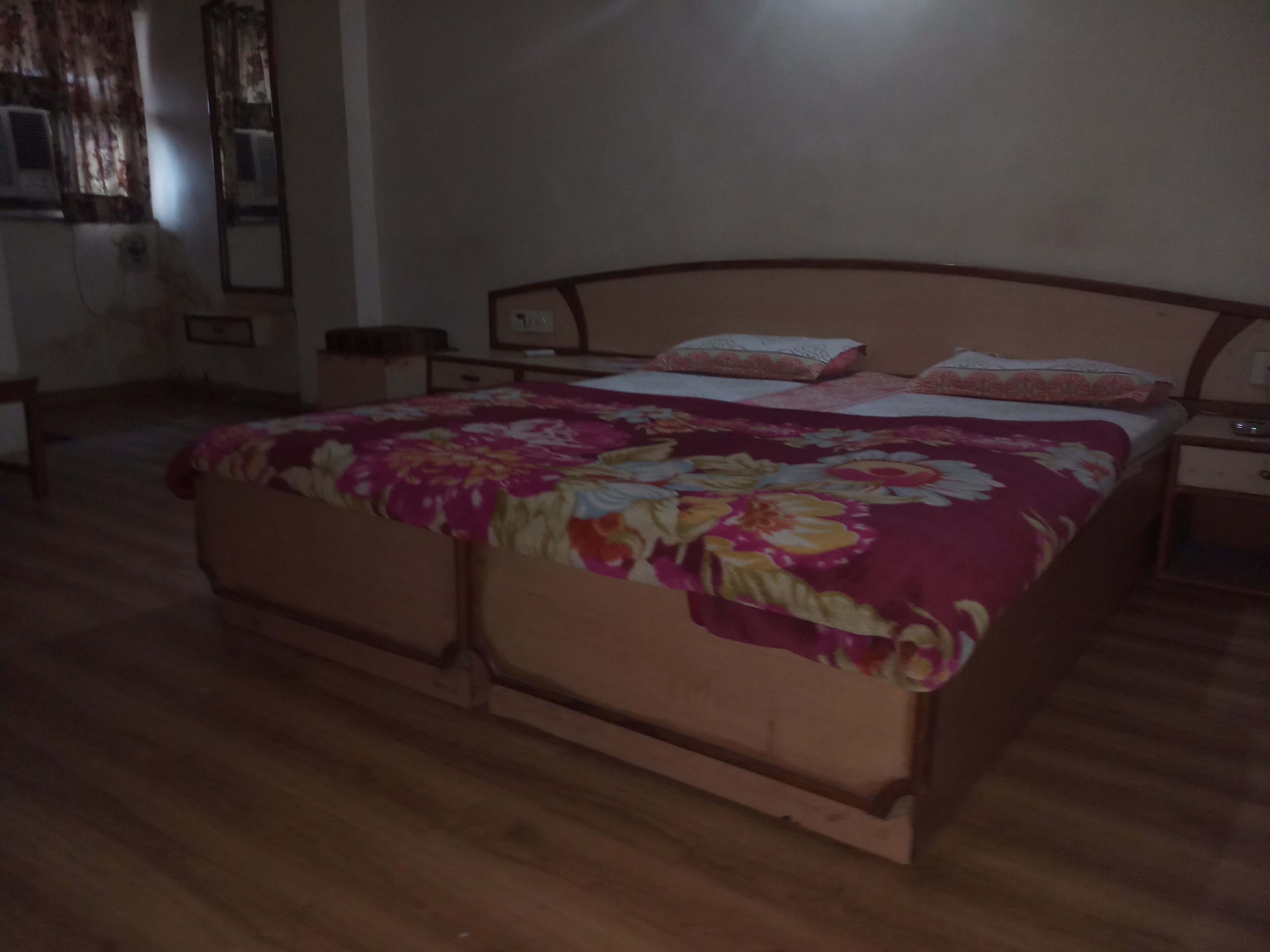 A bedroom with a wooden bed, a nightstand, and a mirror.