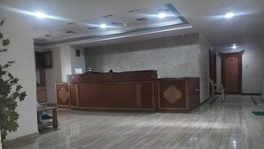 A spacious room with a marble floor, a wooden reception desk, and a ceiling with recessed lighting. - Rajshree Hotel (Ahmedabad)