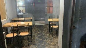 A restaurant with a tiled floor, wooden tables, and metal chairs. - Rajshree Hotel (Ahmedabad)