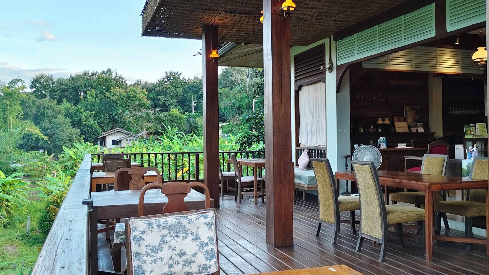 Um deck de madeira com área de estar ao ar livre, bar e vista para vegetação exuberante.