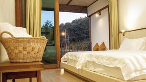 A bedroom with a bed, a wicker basket, and a view of the outdoors. - Sang Poy Cottage (Mae Hong Son)